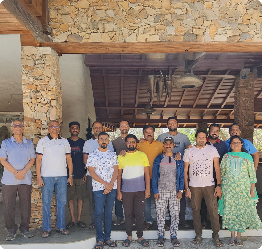 Employees posing together outside a stone building during a team outing.